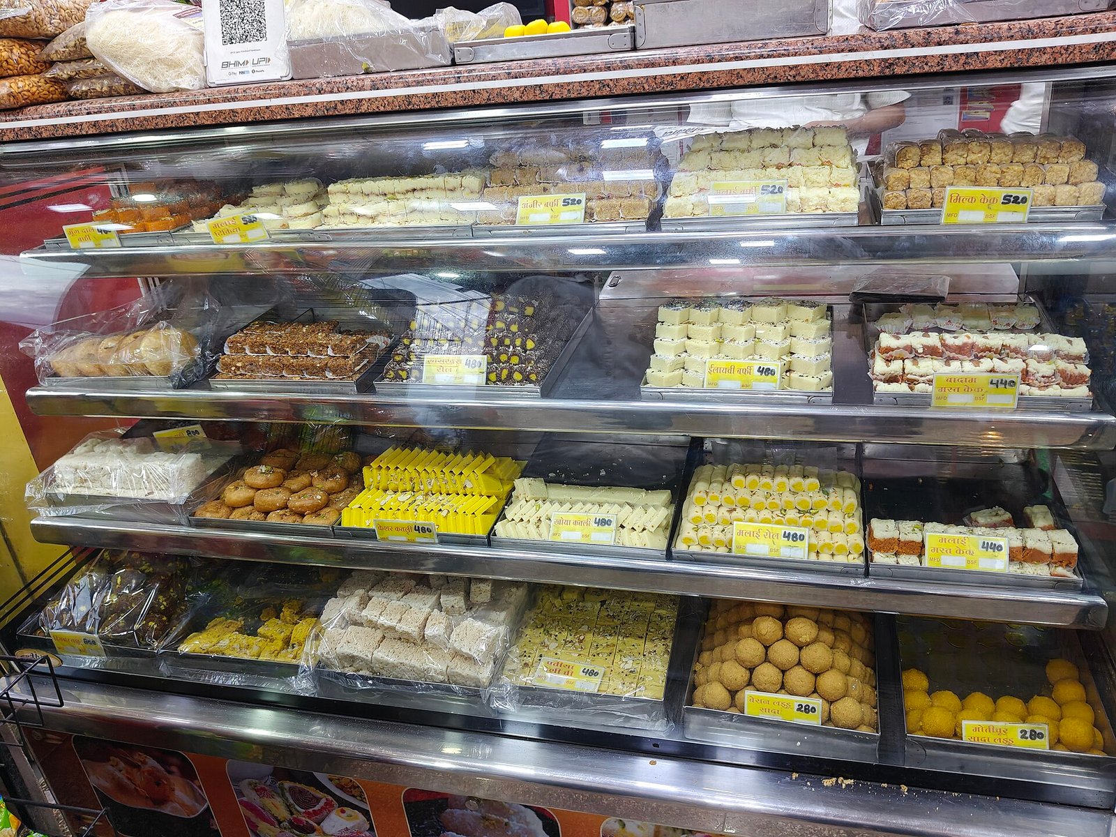 Glass display counters full of colourful Indian mithai at a sweet shop in Dubai