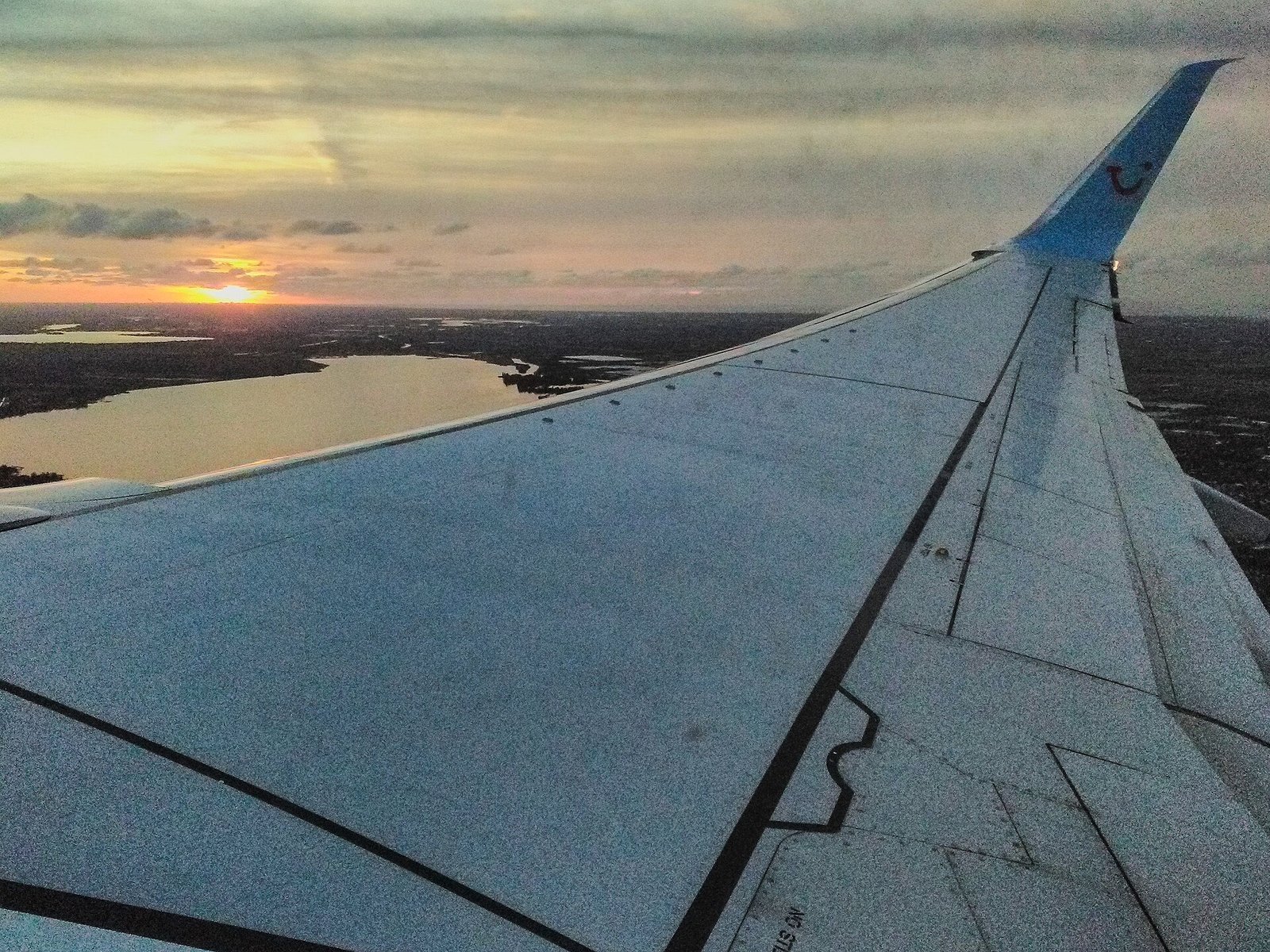 Airplane wing at sunset seen from a passenger window during take-off