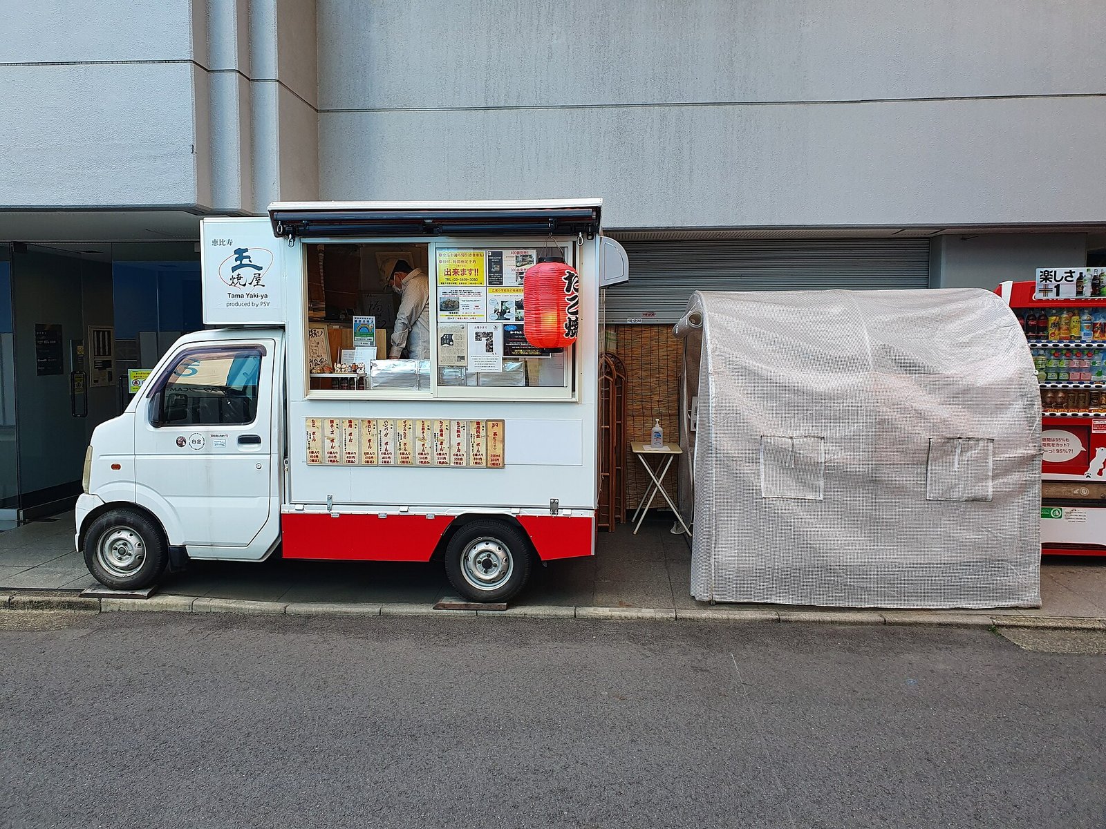 Takoyaki stand with round grilled octopus balls sizzling in cast-iron molds