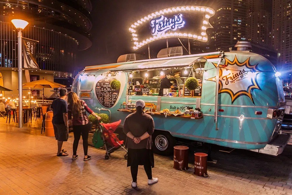 A branded food truck serving customers at an outdoor food event in Dubai