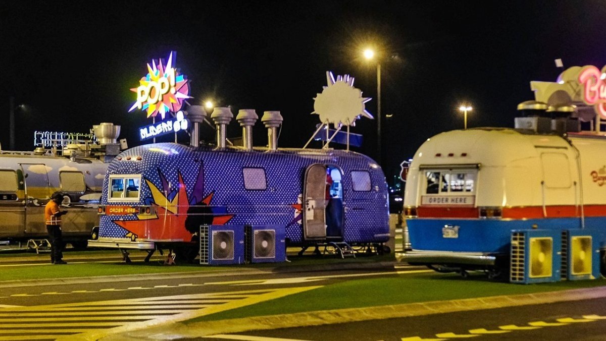 Colourful food trucks lined up at a Last Exit food truck park in Dubai at night